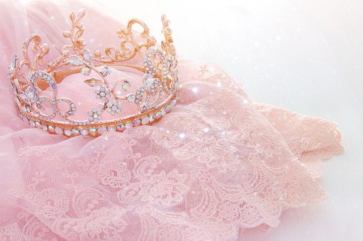 Vintage tulle pink chiffon dress and diamond tiara on wooden white table. Wedding and girl's party concept.