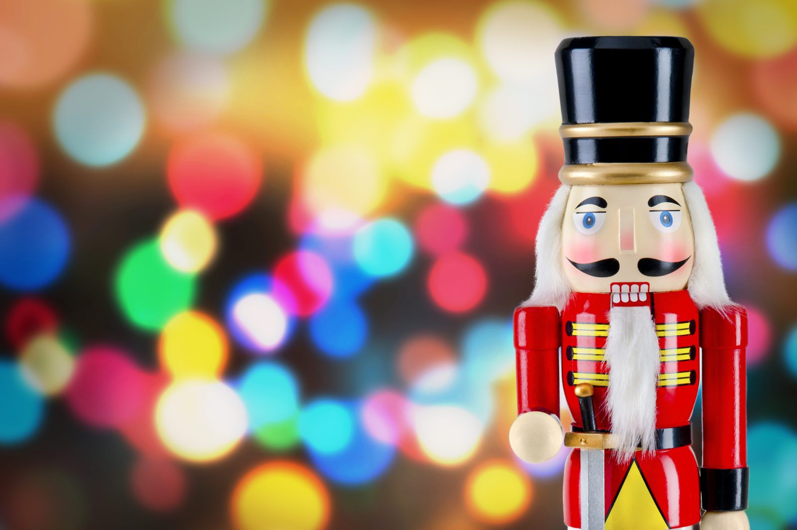 Soldier nutcracker statue standing in front of bright Christmas lights