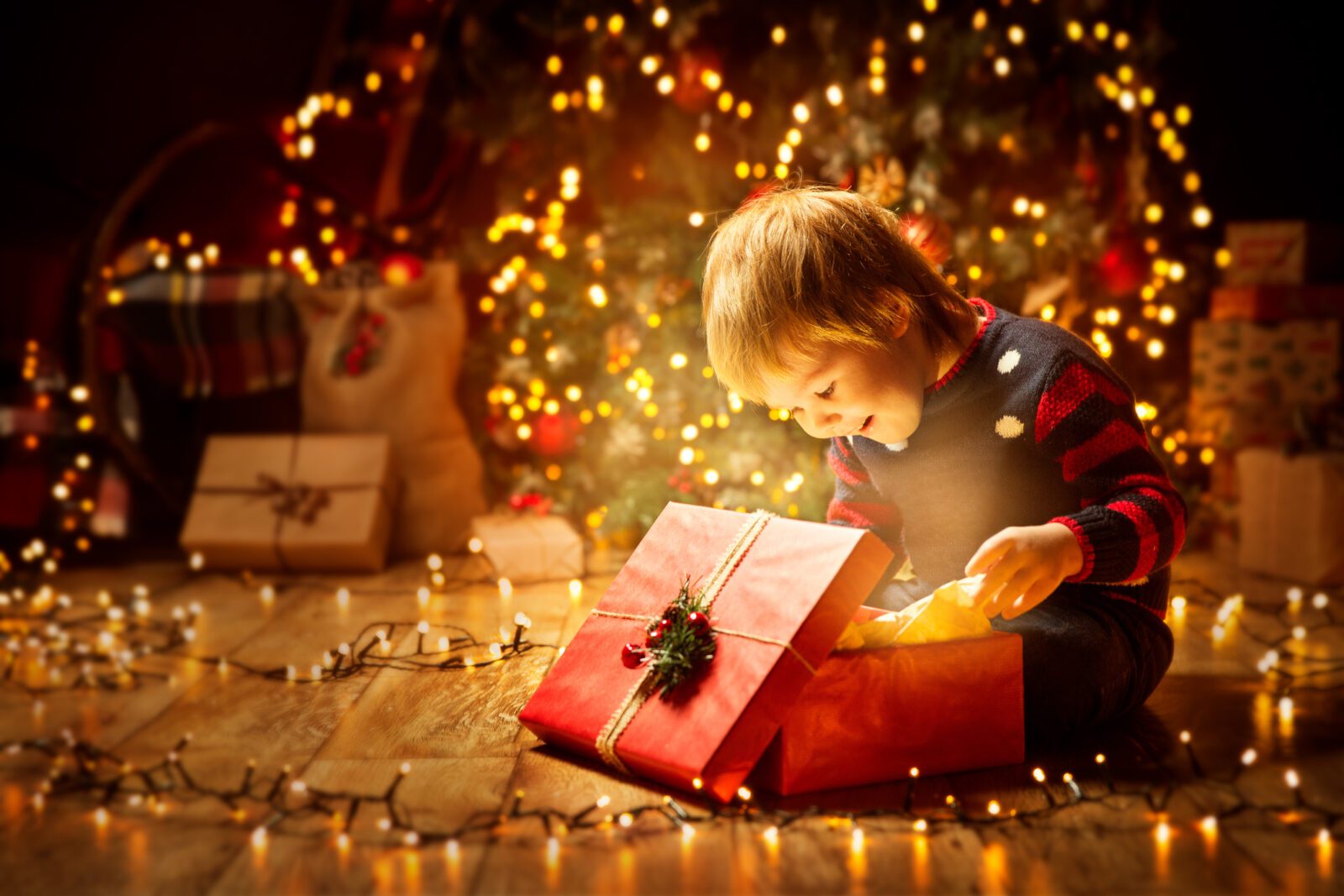 Christmas Child Open Present Gift, Happy Baby Boy looking to Magic Light in Box, Kid and Xmas Tree