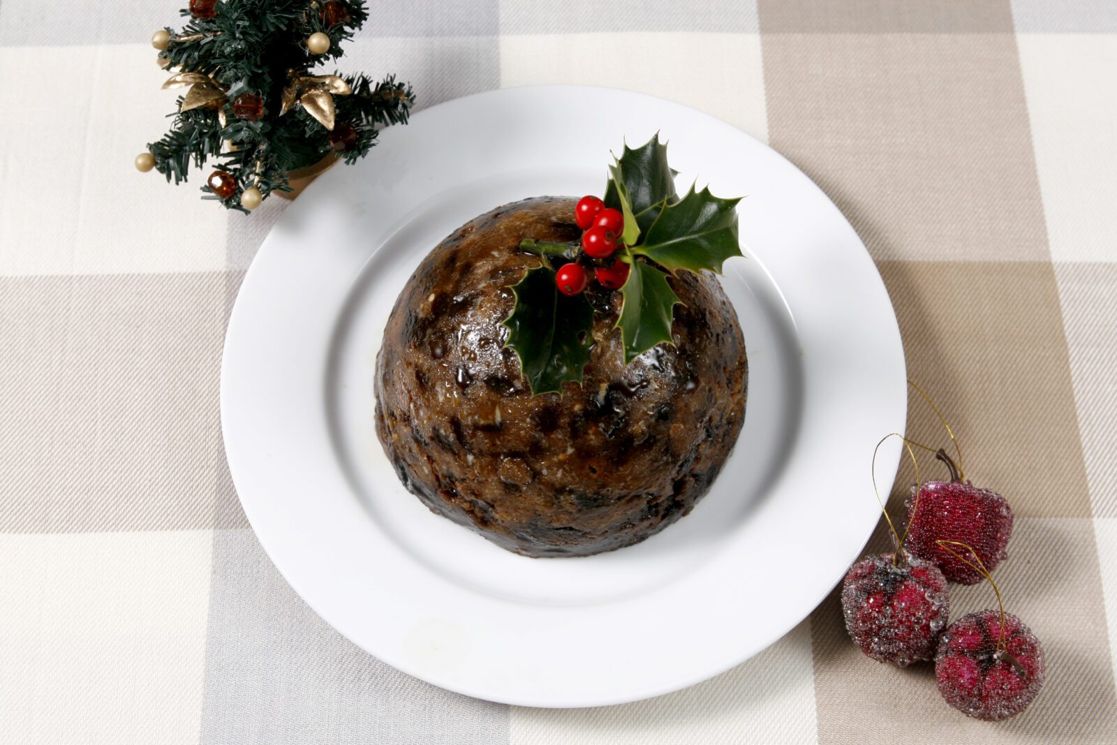 A traditional British Christmas steamed pudding decorate with holly served with custard