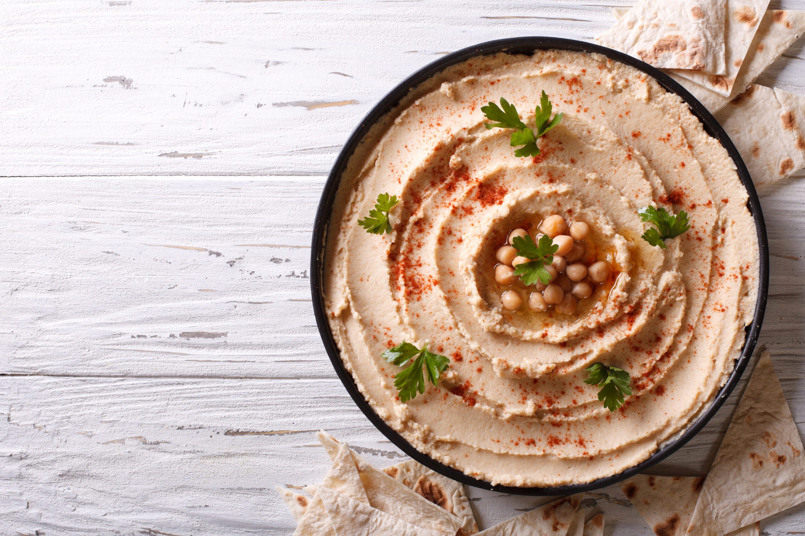 Classic hummus with parsley on tahe plate and pita bread. horizontal top view